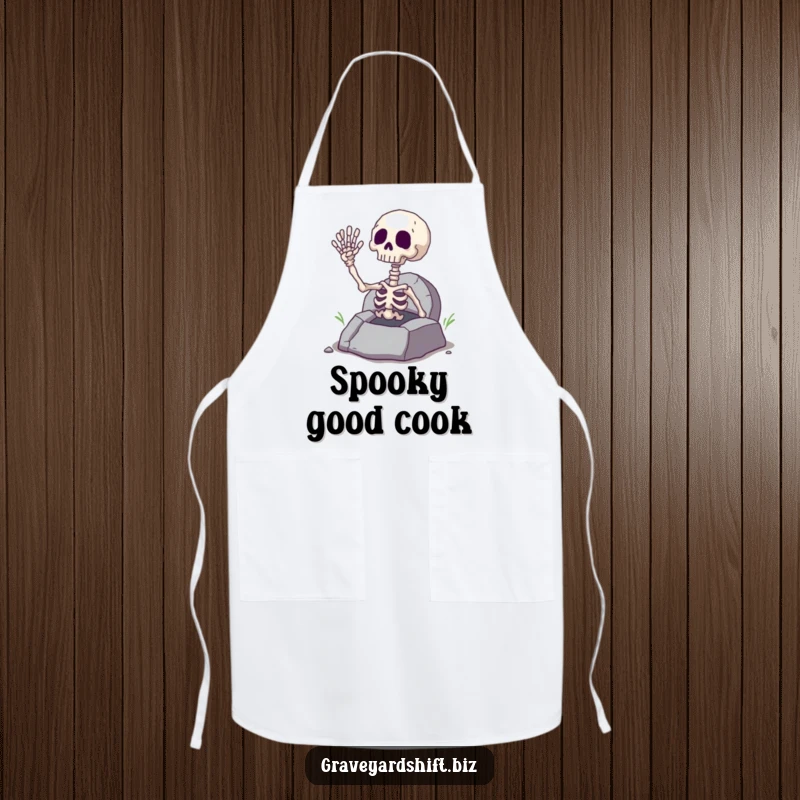 Funny giggling skeleton hand waving from a cracked grave, on a durable apron for spooky chefs and bakers.