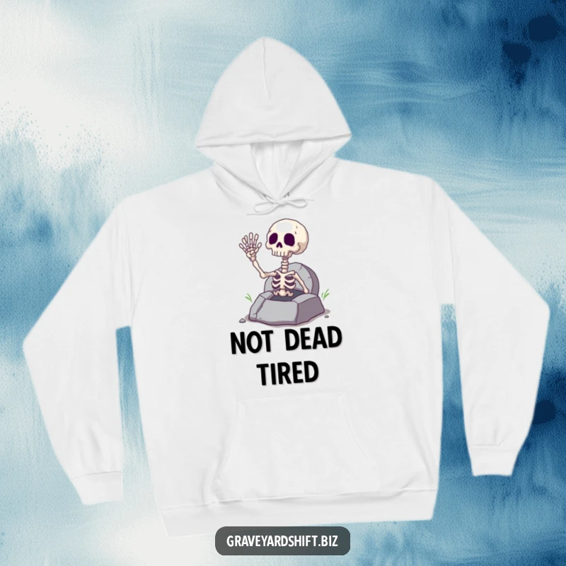 Funny giggling skeleton hand emerging from a cracked grave, printed on a soft hoodie, ideal for spooky season fun.